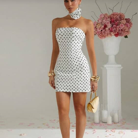 Woman wearing a strapless polka dot dress with a neutral background