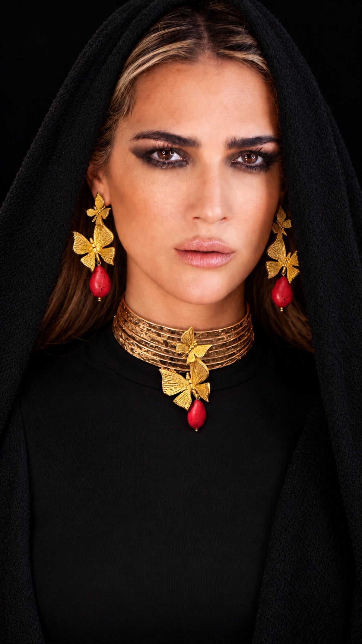 Model wearing handmade gold leaf butterfly earrings and choker necklace with red coral stone drops